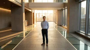 Un homme d'affaires confiant debout dans un hall moderne et lumineux au coucher du soleil.